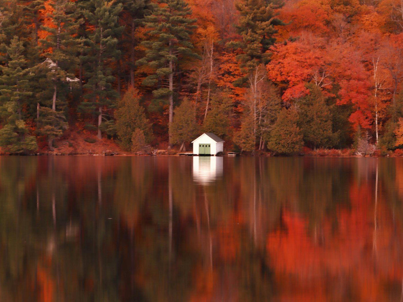 A lakeside cottage among autumn trees